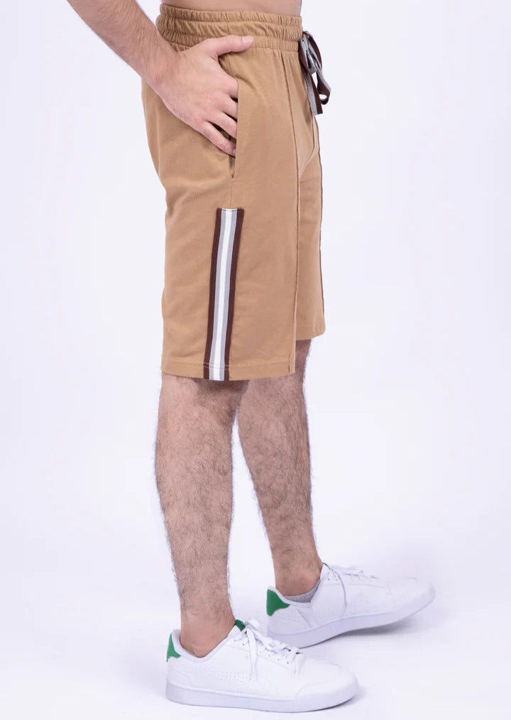 Person wearing tan shorts with a white stripe on a white background